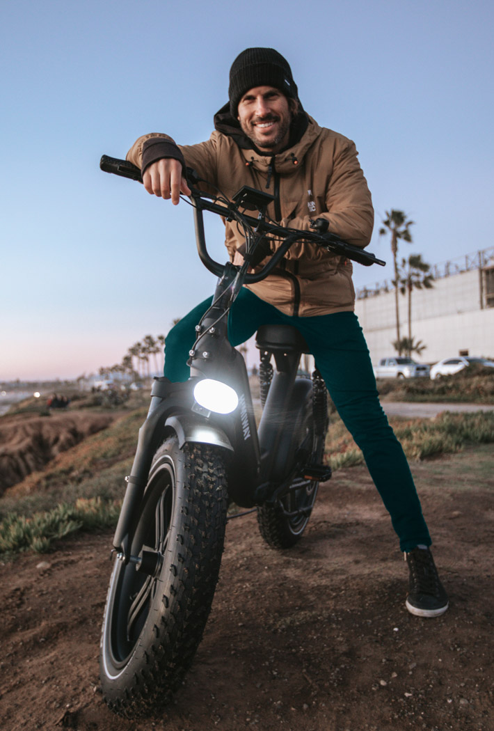 Mann posiert auf Mountainbike an einem Küstenabschnitt.