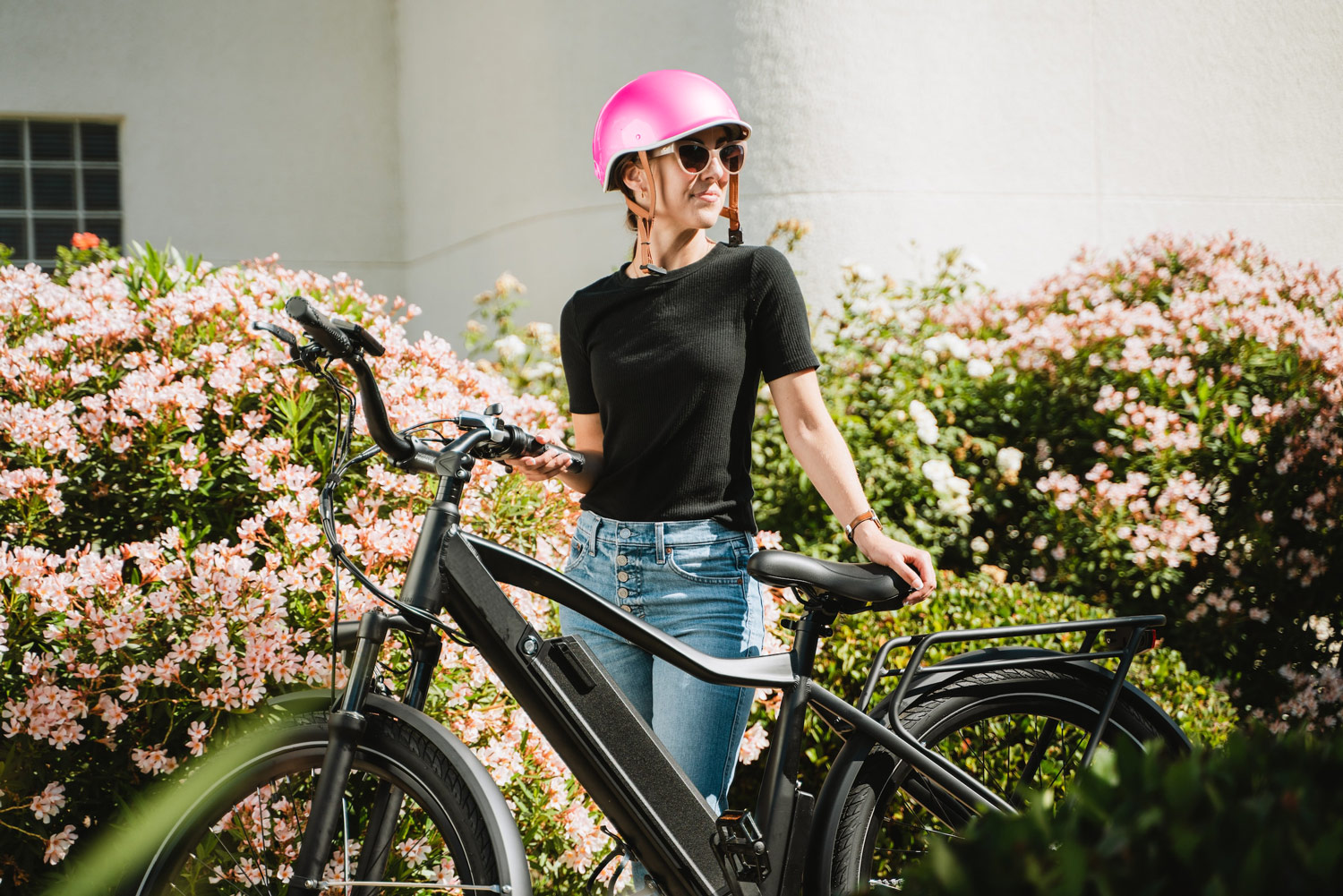 Frau mit E-Mountainbike und rosa Helm