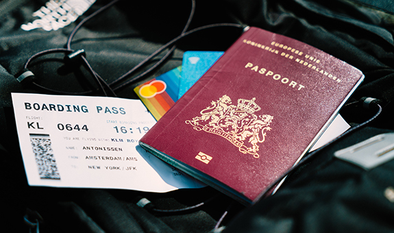 Schwarzer the North Face Rucksack auf dem ein niederländischer Reisepass, zwei Kreditkarten und eine Bordkarte liegen.