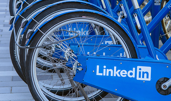 Reihe von blauen Fahrrädern mit weißen LinkedIn Logo auf dem Rahmen.